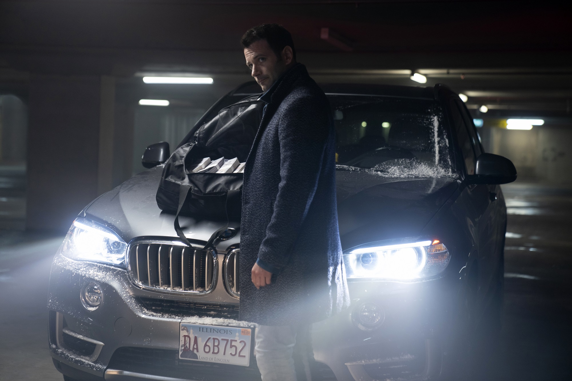'Irreverent' on Peacock: Colin Donnell as Mack/Paulo standing in front of a car