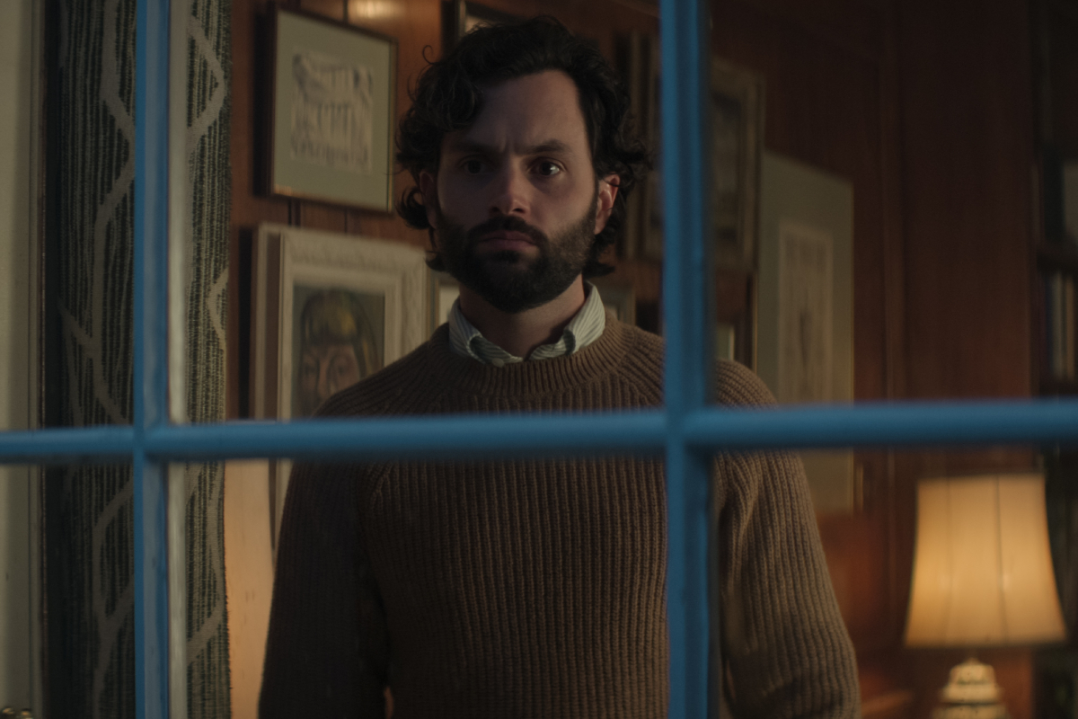 In You Season 4, Joe Goldberg stares out of his window wearing a sweater with a collared shirt underneath.