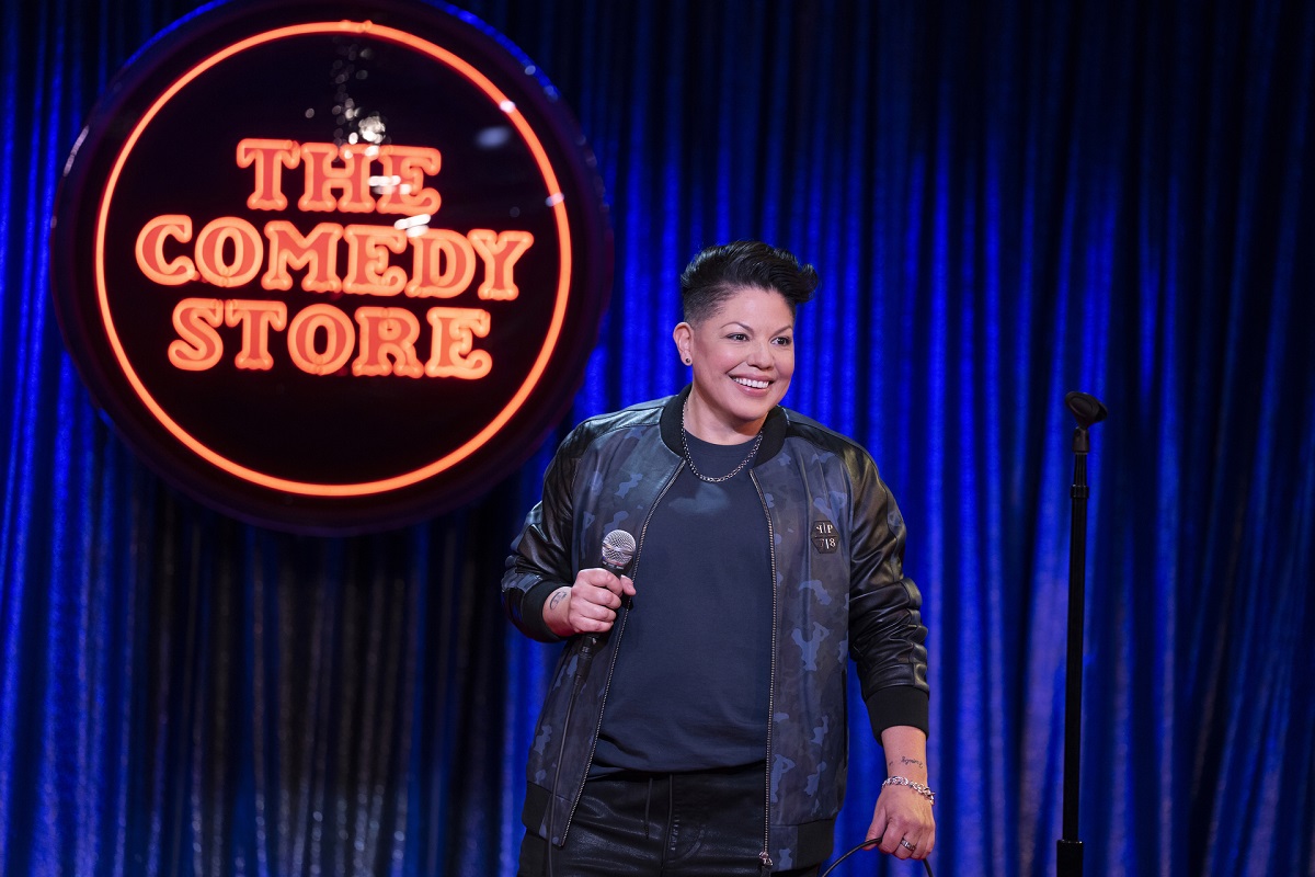 Sara Ramirez as Che Diaz stands in front of a 'The Comedy Store' sign in 'And Just Like That...' season 2