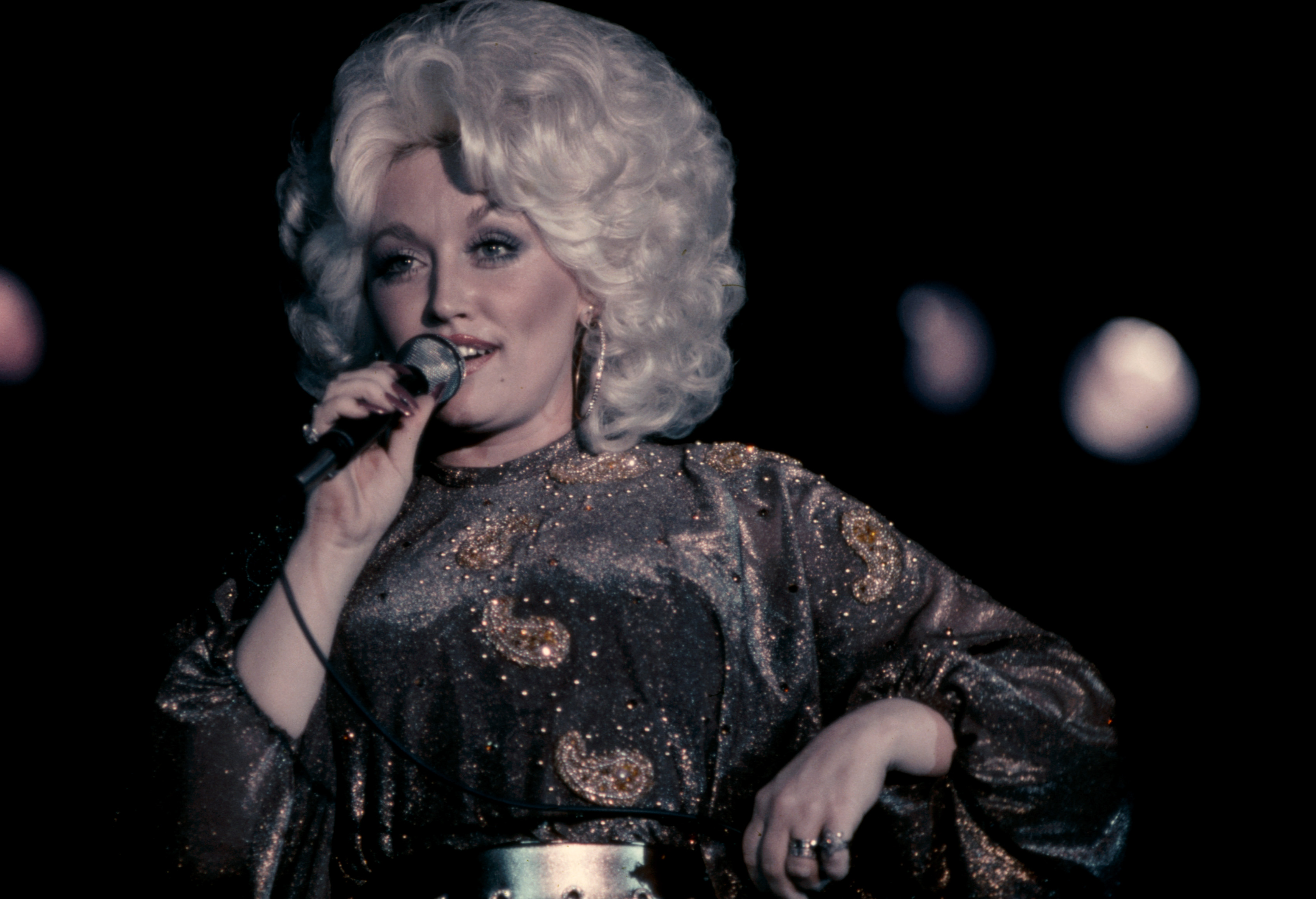 Dolly Parton sings into a microphone.