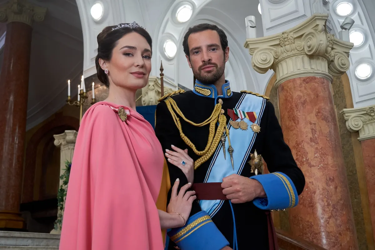 Woman in a pink dress standing next to a man wearing a sash