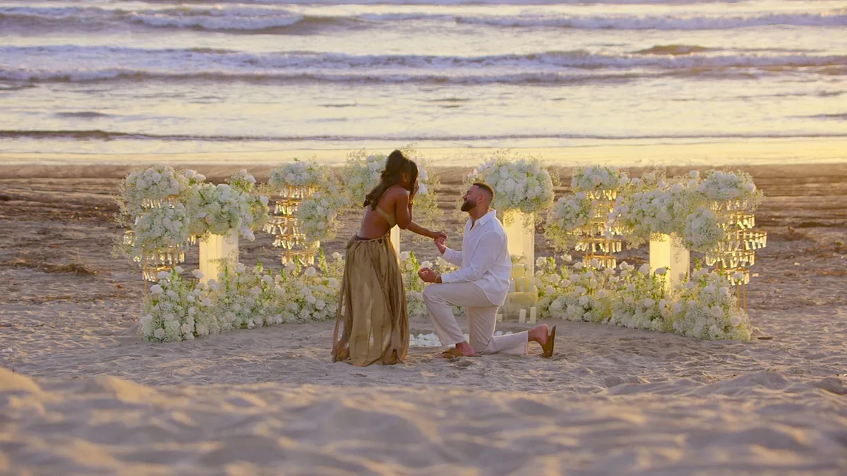 Ollie gets down on one knee to propose to AD on a beach