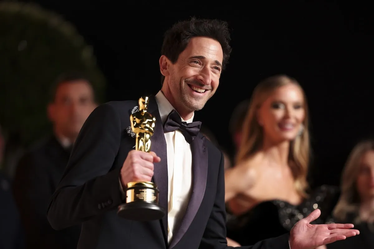 Wearing a black tuxedo, Adrien Brody laughs on the red carpet at the 2025 Vanity Fair Oscar Party