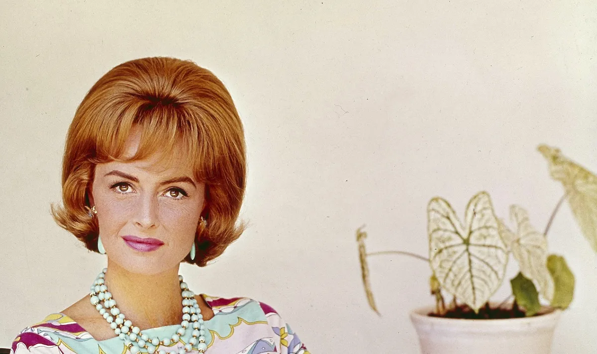 Donna Reed sitting next to a philodendron