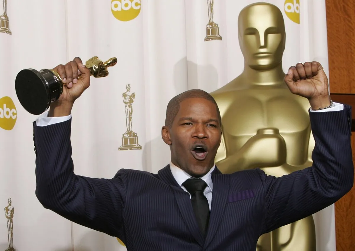 Jamie Foxx posing while holding an Oscar.