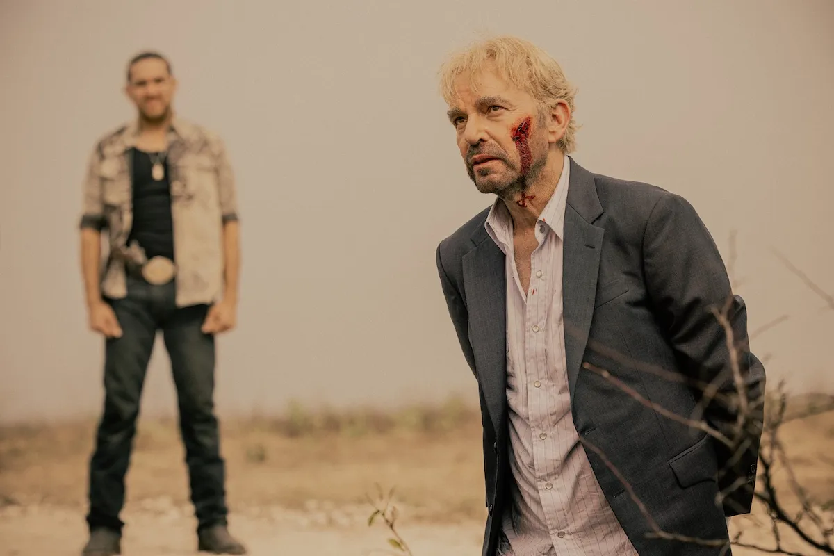 BIlly Bob Thornton, with a bloody face, kneels with his hands behind his back in 'Landman'