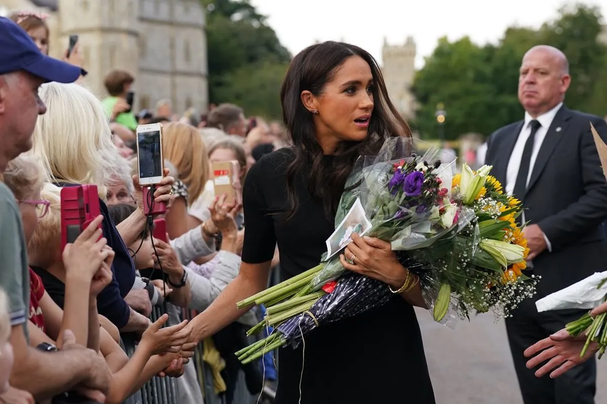Meghan Markle collects flowers as she greets well-wishers on the Long walk at Windsor Castle