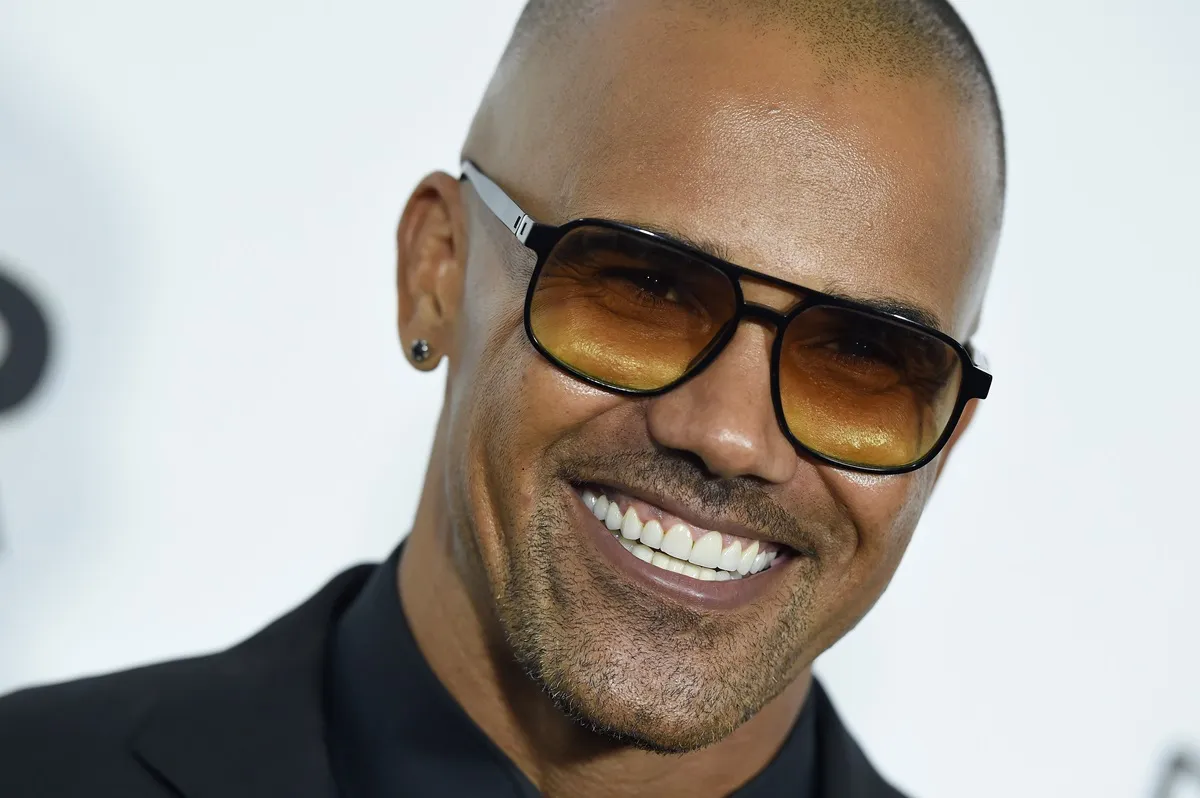 Shemar Moore smiling at amfAR's Inspiration Gala Los Angeles at Milk Studios in a black suit and shades.