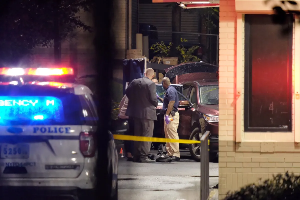 Cops looking at a car with a squad car and crime scene tape in the foreground