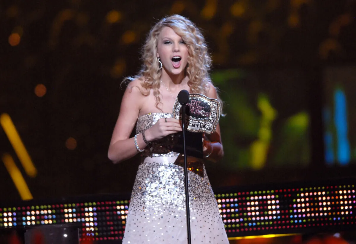Taylor Swift wears a sparkly silver dress and accepts an award.